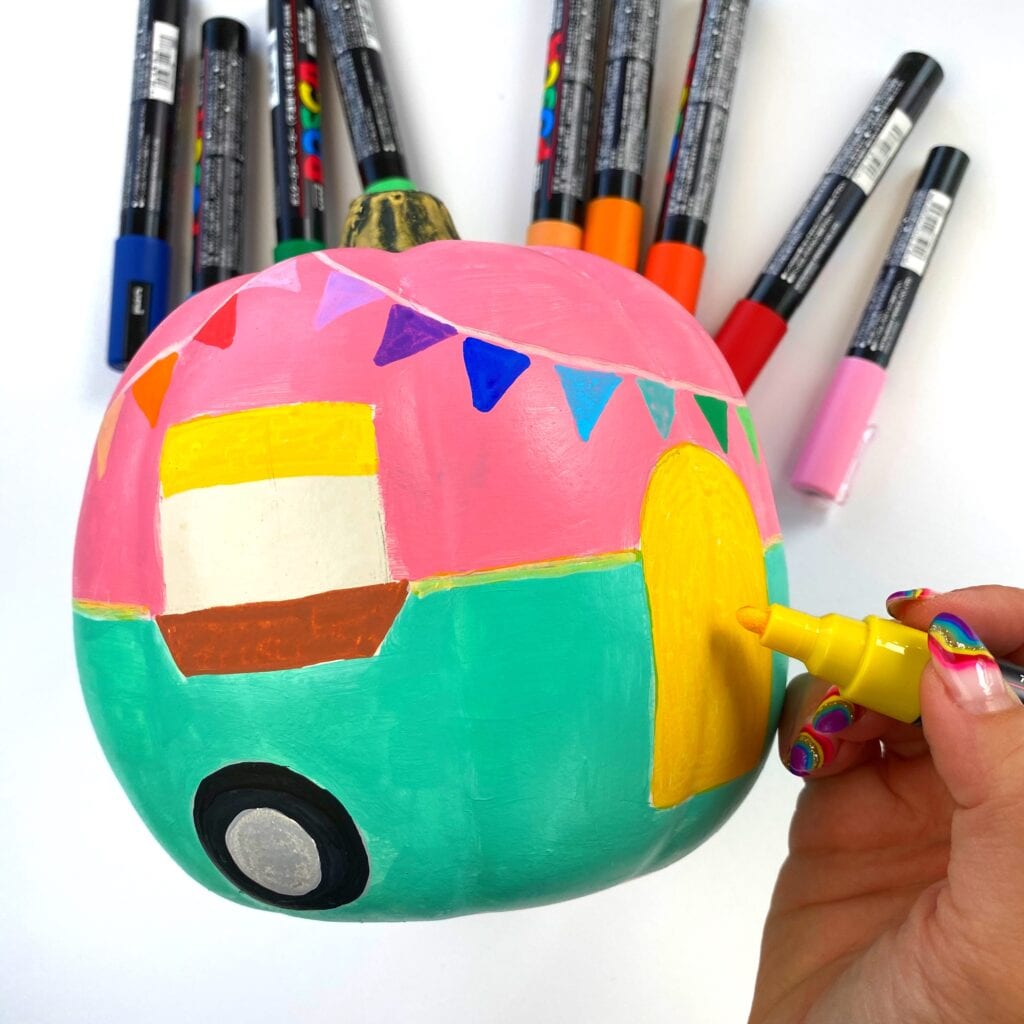 Adding fine details to our camper themed pumpkin with paint markers